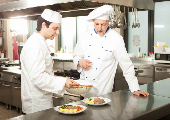 Chef giving sous-vide cooking advice to another chef