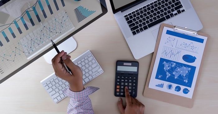 Photography of a man in front of computers with a calculator