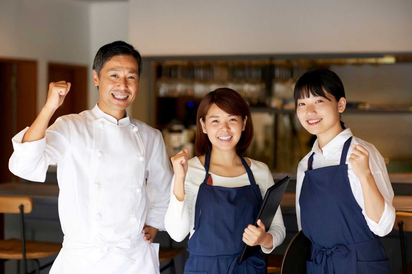 Three restaurant workers fist pumping and smiling