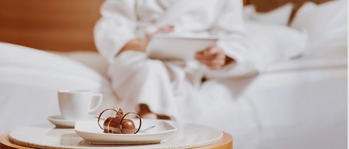 Guest in bathrobe using tablet in hotel