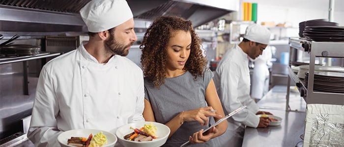 Chef and manager discussing menu ideas in a bustling kitchen