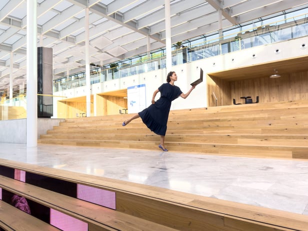 A woman balancing on one foot and holding a laptop in her hand to showcase the balancing act between career and motherhood. 