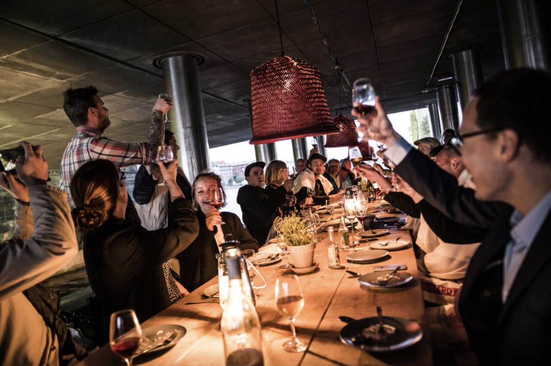 Happy people raising a glass along a table in Noma pop-up restaurant