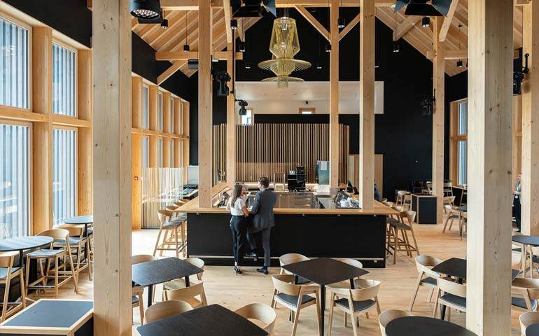 Modern coffee shop with wooden beams and black walls, offering a chic and inviting atmosphere for guests