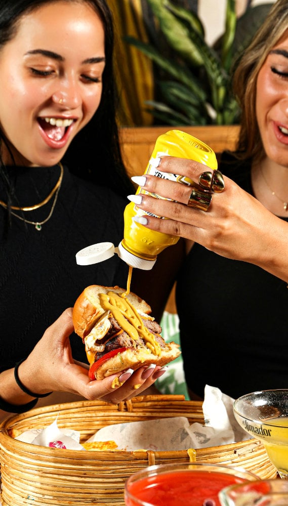 Woman eating a burger with a cocktail