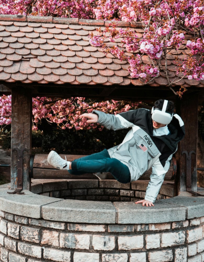 Guy jumping over a well with cherry blossoms in the background