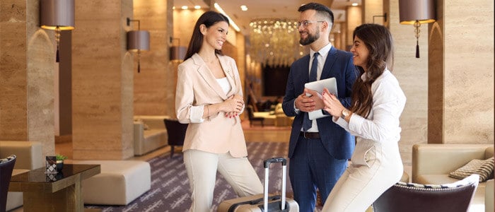 Two happy hotel guests standing together with the manager in a hotel lobby, smiling