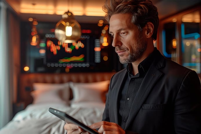  A man uses a tablet in a hotel room, focusing on hotel demand management