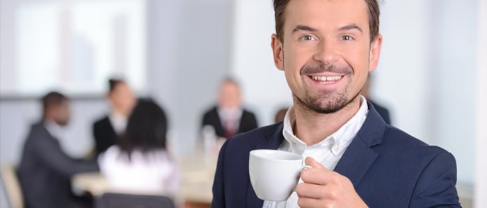 hotel staff meeting with the manager in a suit holding a coffee cup