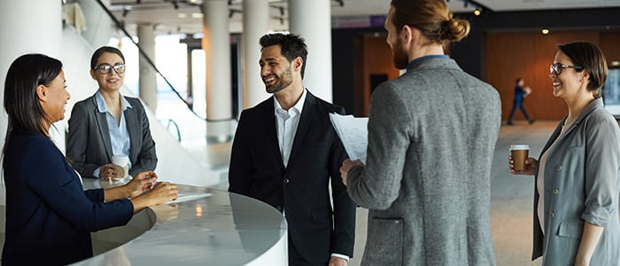 a diverse group of individuals interacting near a reception desk, showcasing collaboration and professional engagement