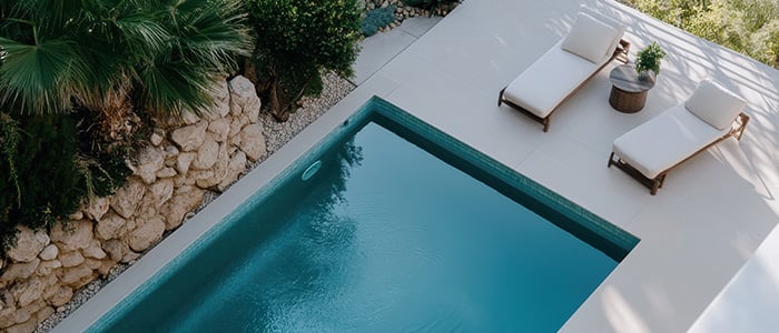 luxurious pool area featuring lounge chairs and a small garden
