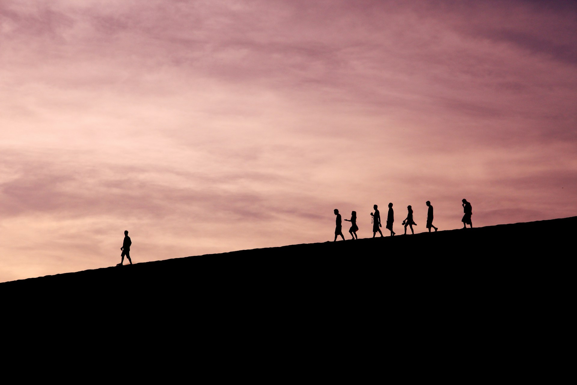 Silhouette of a person leading a team of people on a mountain trail