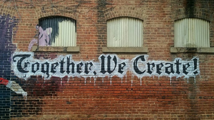 Graffiti art on a brick wall that reads "together we create"