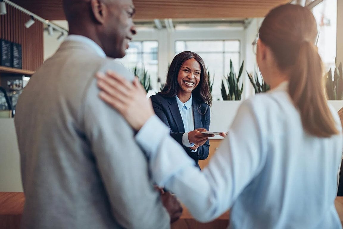 Two women and a man engage in a business conversation in a hospitality setting